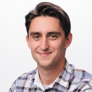 Tudor smiles for the camera in a professional headshot with a simple background.