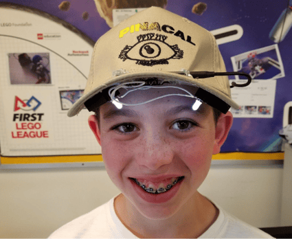 A young student from the RoboHawks poses with a very early iteration of the Pinacal