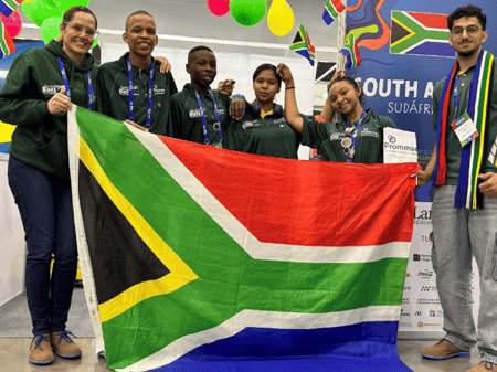 Team South Africa smiles and poses with a large and small version of their country's flag.