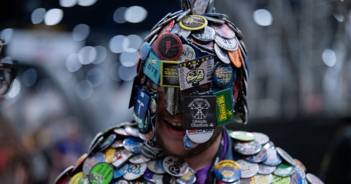A close up headshot of the Button Master with his button helmet and jacket. He is smiling.