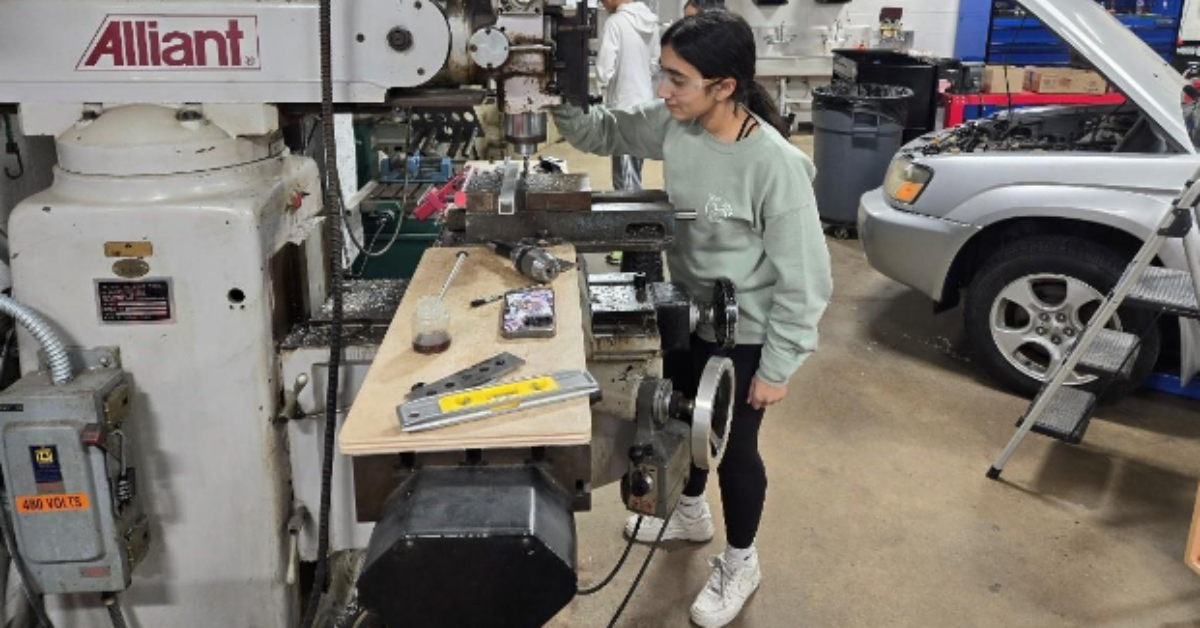A student stands at a workbench in their robotics shop.