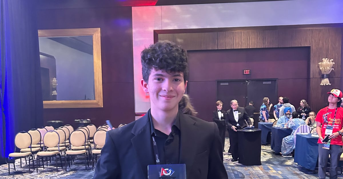 Thalis stands smiling and posing with his award.