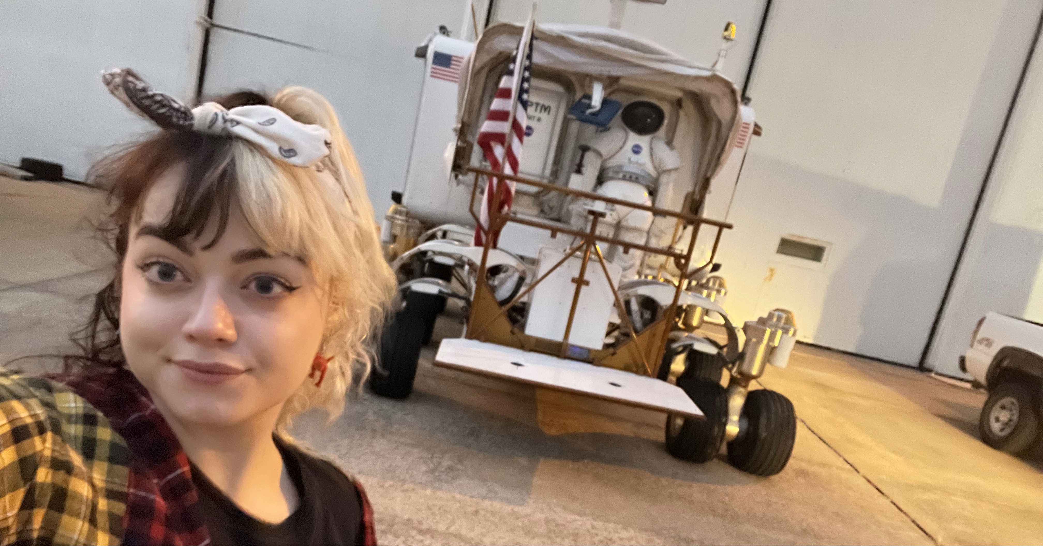 Jenna stands and poses in front of a NASA vehicle.