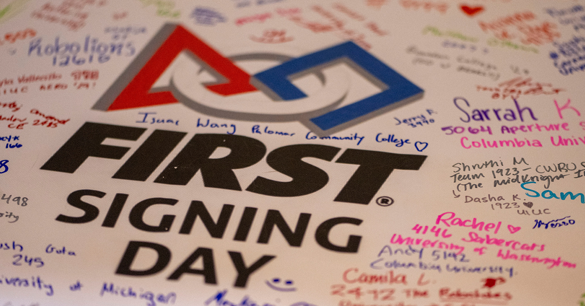The FIRST Signing Day logo sits on a big white paper, surrounded by differently colored signatures and post-FIRST declarations.