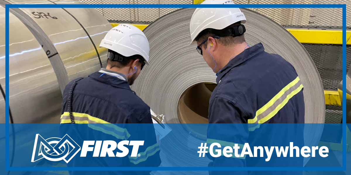 Michael and a colleague inspect a roll of aluminum. The FIRST logo and Get Anywhere hashtag are over a transparent blue background at the bottom of the image.