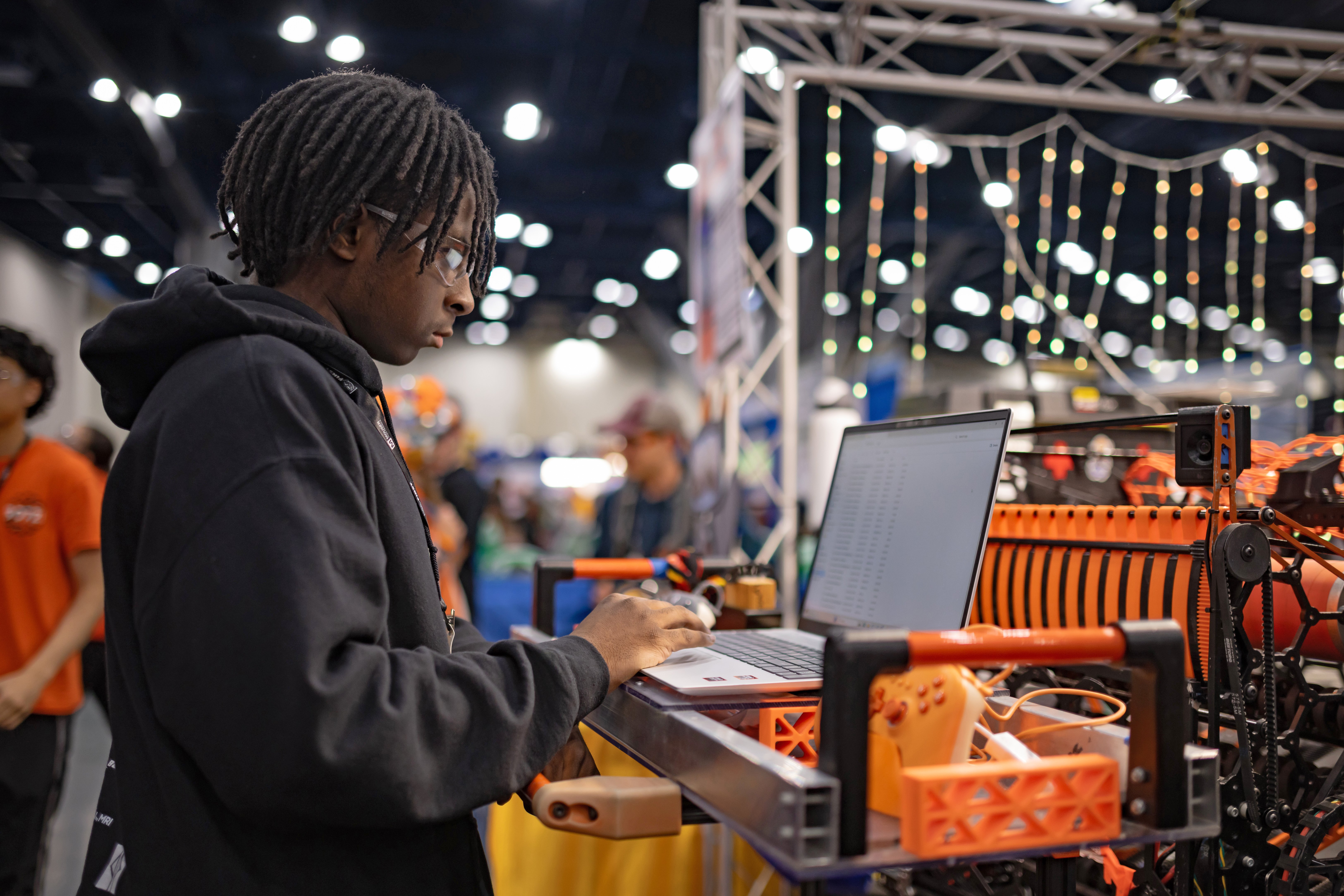 student in the robotics competition pits working on a laptop.